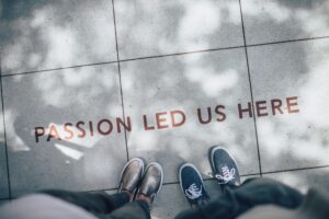 this is an image of a team standing with focus on their feet where they are standing and there a sentence reads passion led us here depicting purpose as this image is for a post on brand purpose.